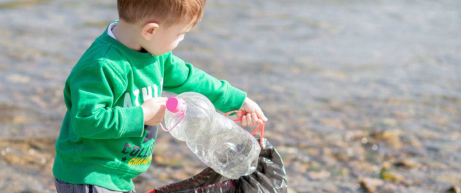 Niño recogiendo botellas usadas para su reciclaje